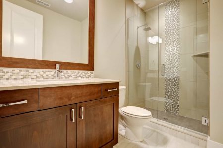 Glass walk-in shower with white subway tiled surround accented with vertical mosaic tile strip in brand-new home bathroom. Northwest, USA